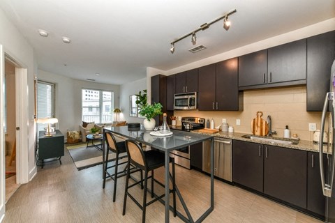 a kitchen with an island and stools and a living room with a couch